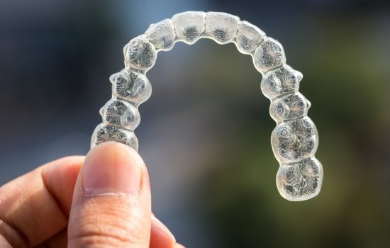 Hand holding an Invisalign clear aligner