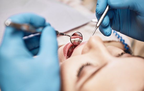 Dentist using dental mirror to examine patient's teeth