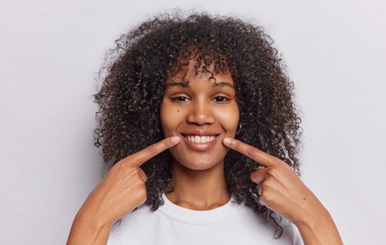 a woman pointing at her new and improved smile