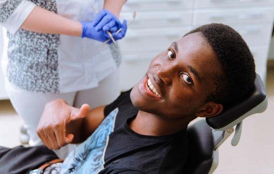 Man giving thumbs up in dental chair