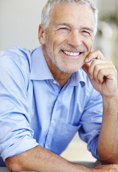 Man in blue collared shirt smiling after replacing missing teeth in Shelburne