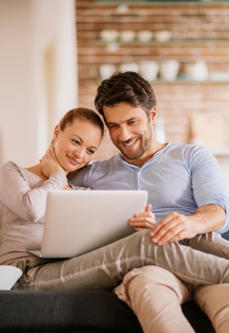 Man and woman on couch with tablet reading dentist reviews in Shelburne