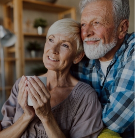 Senior man and woman hugging while looking out window