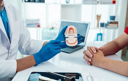 Dentist using tooth model to explain complex concept to a patient