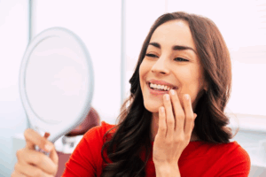 Woman admiring her dental bonding in a small mirror